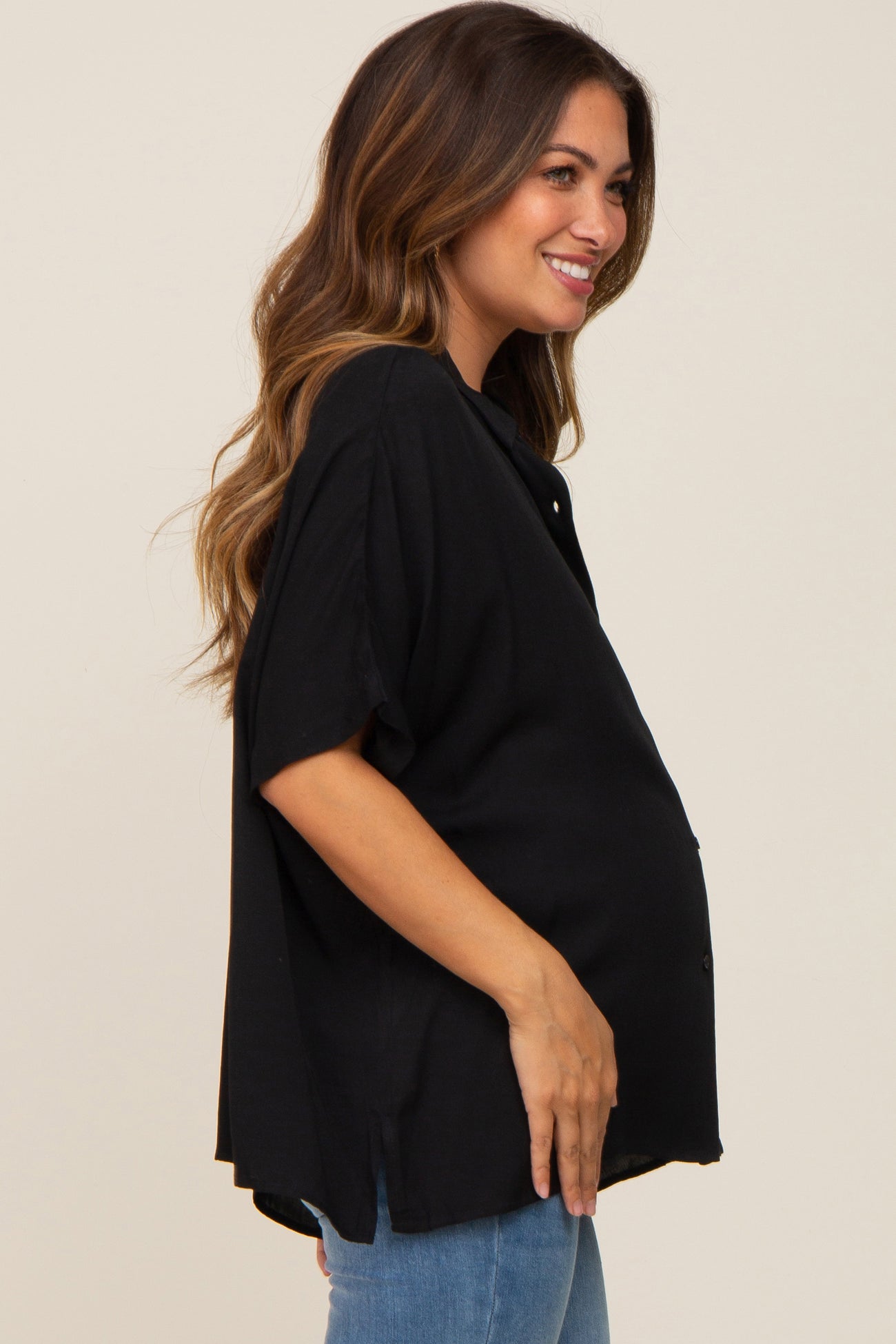 woman wearing a black short sleeve maternity top and holding her baby bump
