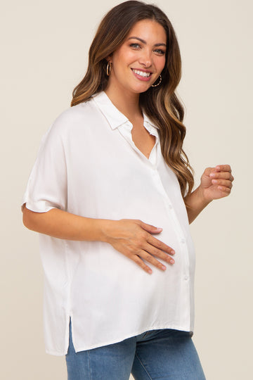 woman wearing a white short sleeve maternity blouse and showcasing her baby bump