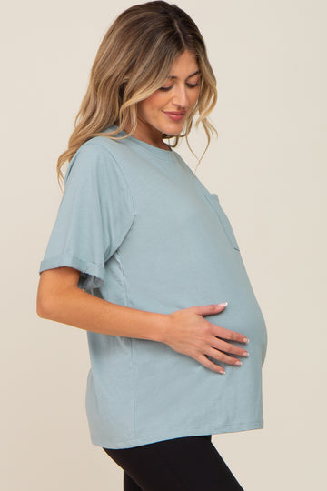woman wearing a light blue short sleeve maternity top and holding her baby bump