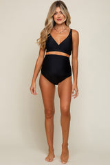 woman wearing a black maternity bikini with a supportive top and high-waisted bottoms, showcasing her baby bump
