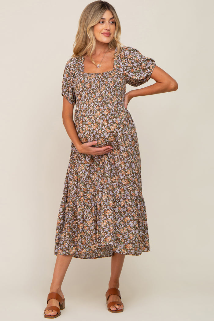 woman wearing a brown floral maternity dress with short puff sleeves and a square neckline, holding her baby bump