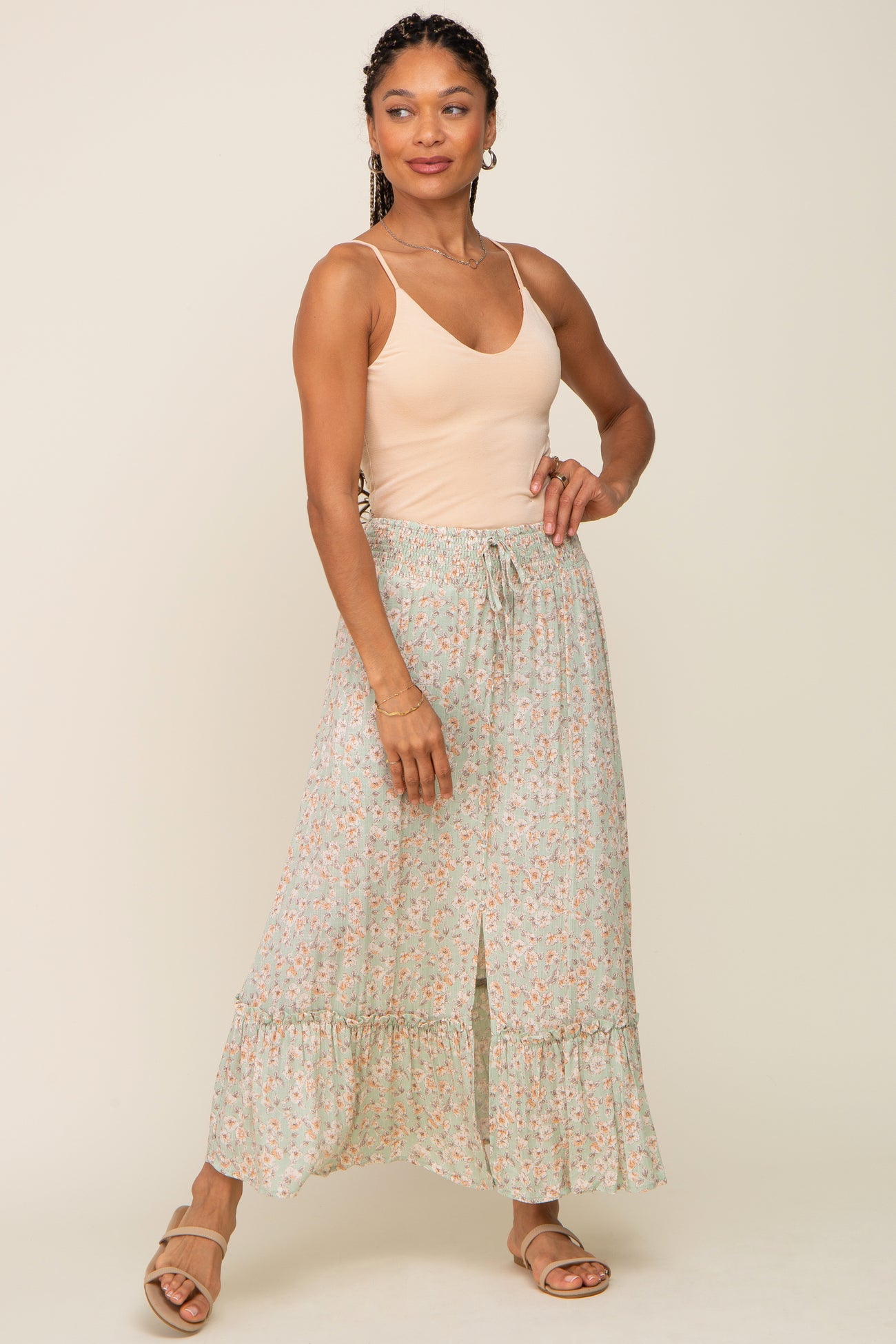 woman wearing a peach camisole and a mint green floral maxi skirt with a ruffled hem and front slit
