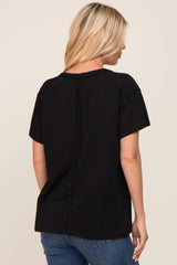 woman wearing a black short sleeve top with a relaxed fit and a back seam detail, seen from the back