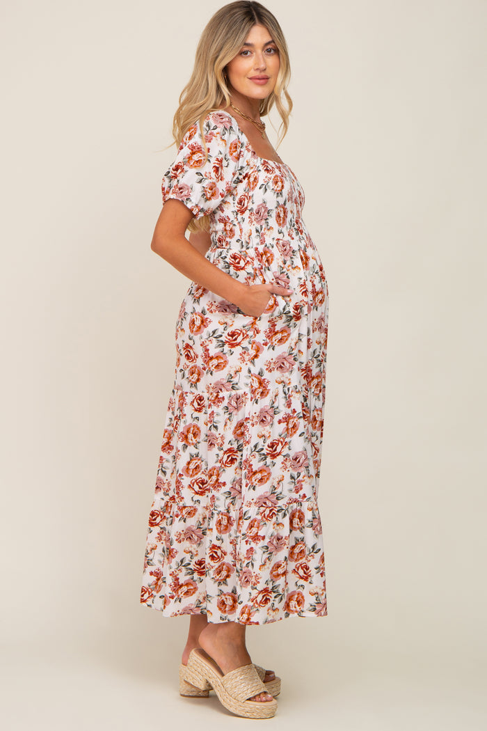 woman wearing a white floral maternity dress with short sleeves and pockets, showing her baby bump