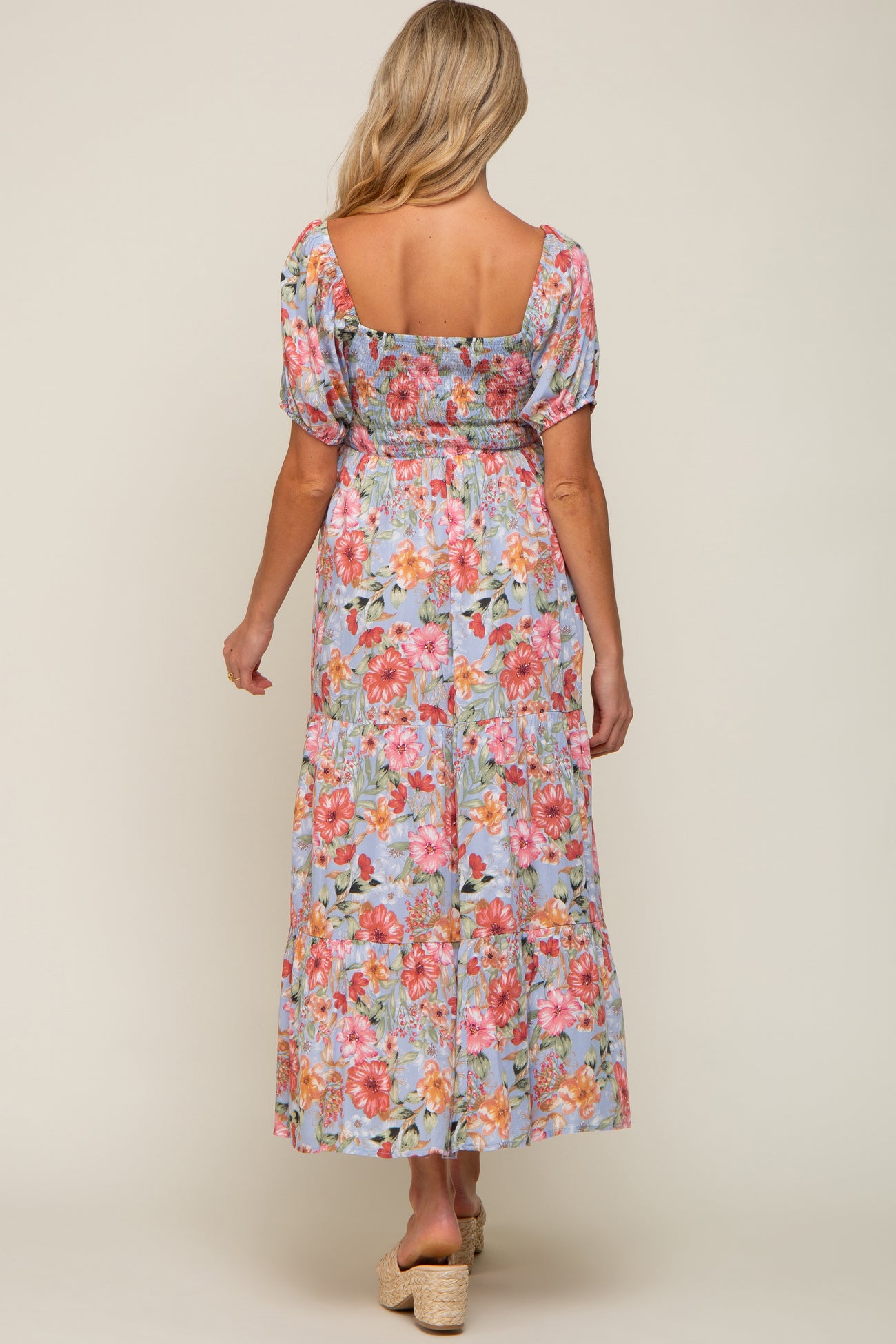 woman wearing a floral maternity maxi dress with puff sleeves and a smocked bodice, showing a comfortable fit for a baby bump