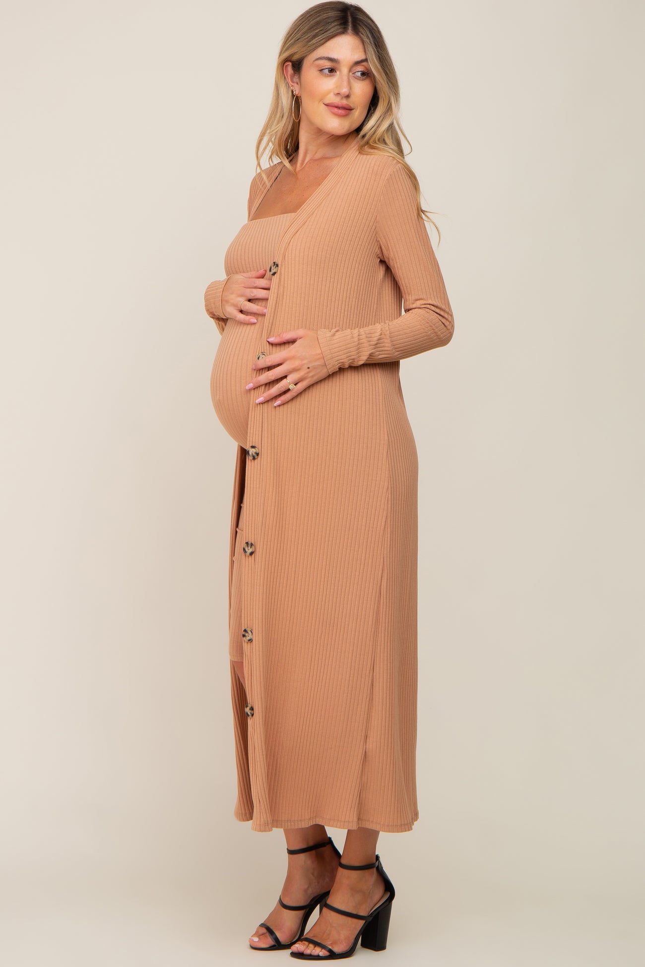 woman wearing a tan ribbed maternity dress with buttons and holding her baby bump
