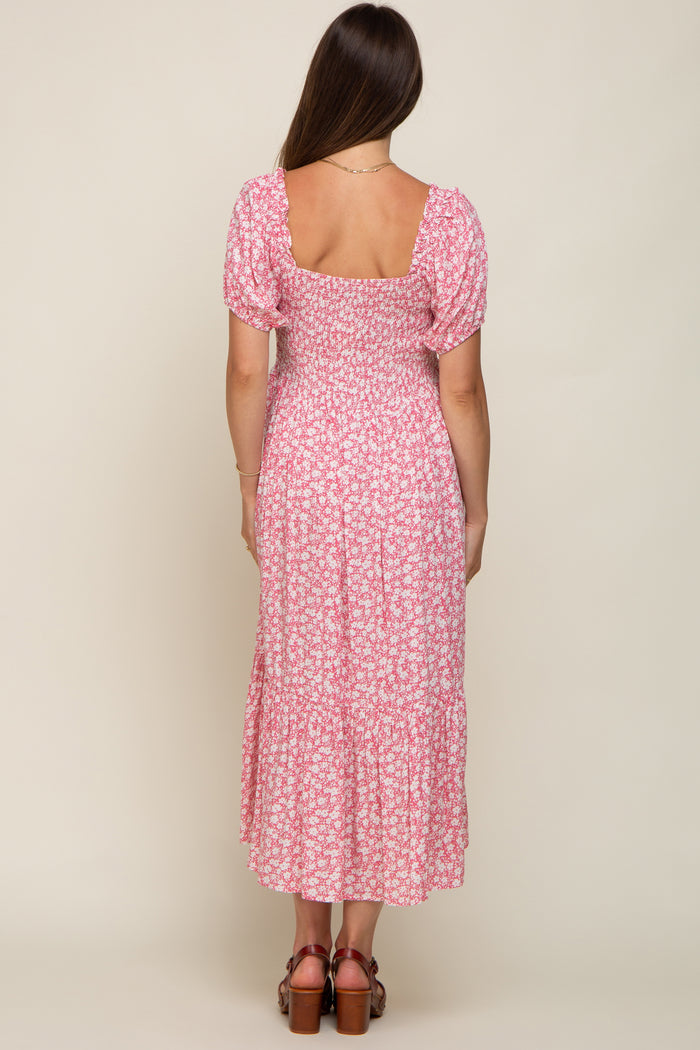 woman wearing a pink floral maternity maxi dress with puff sleeves and a tiered skirt, showing a baby bump