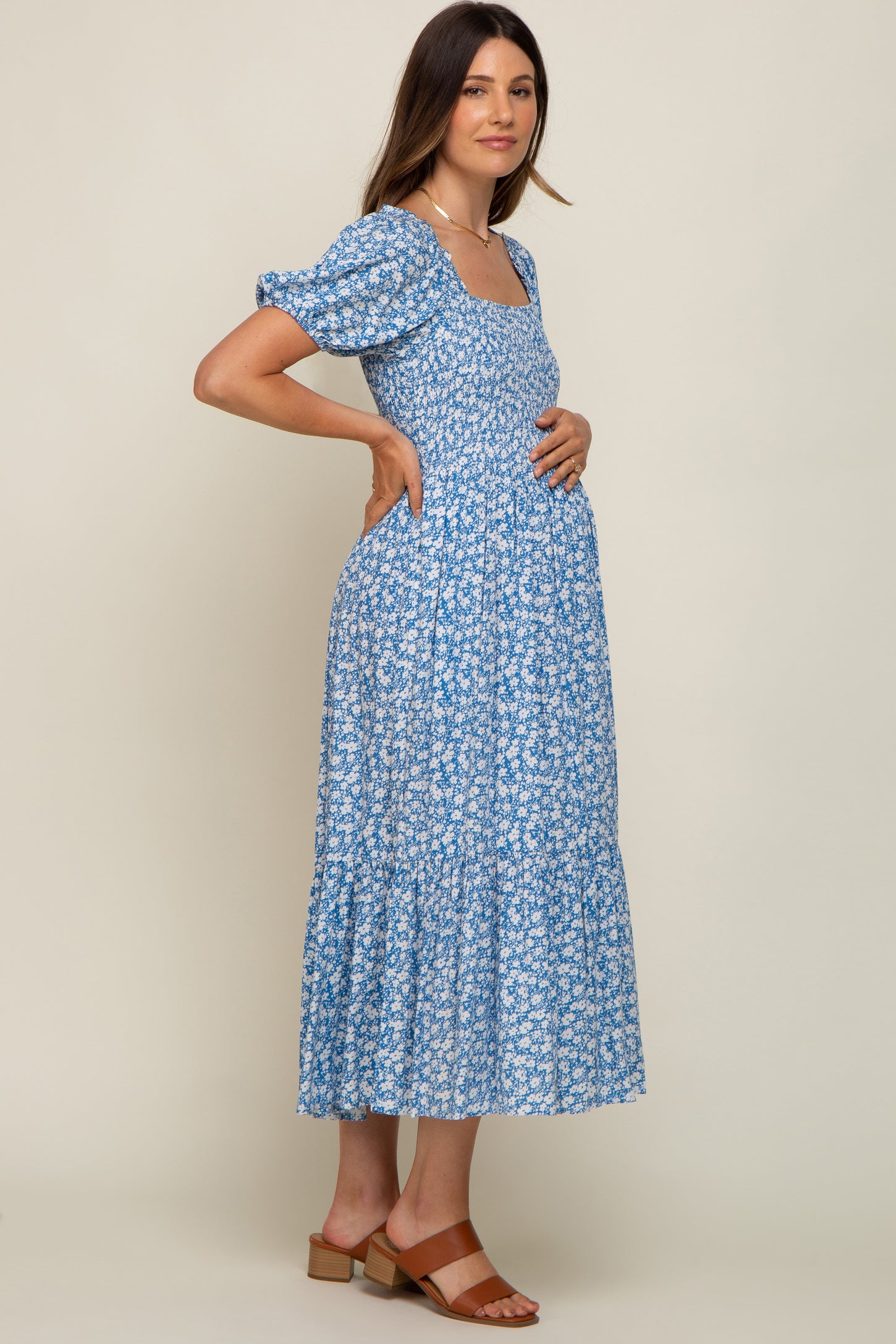 woman wearing a blue floral maternity dress with short puff sleeves and a visible baby bump