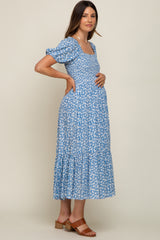 woman wearing a blue floral maternity dress with short puff sleeves and a visible baby bump