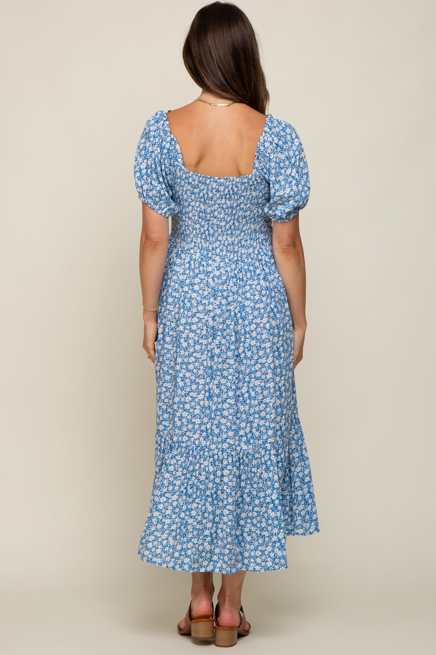 woman wearing a blue floral maternity dress with puff sleeves and a fitted bodice, showing her back