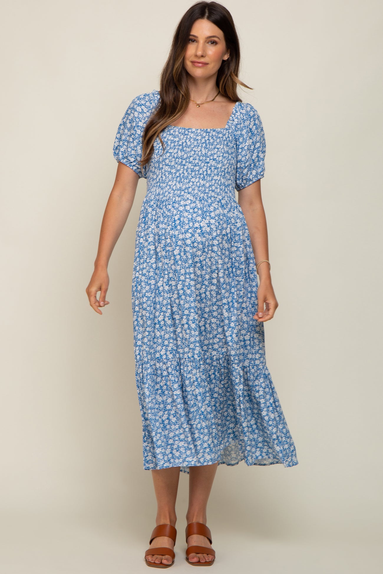 woman wearing a blue floral maternity dress with puff sleeves and a square neckline, showing her baby bump