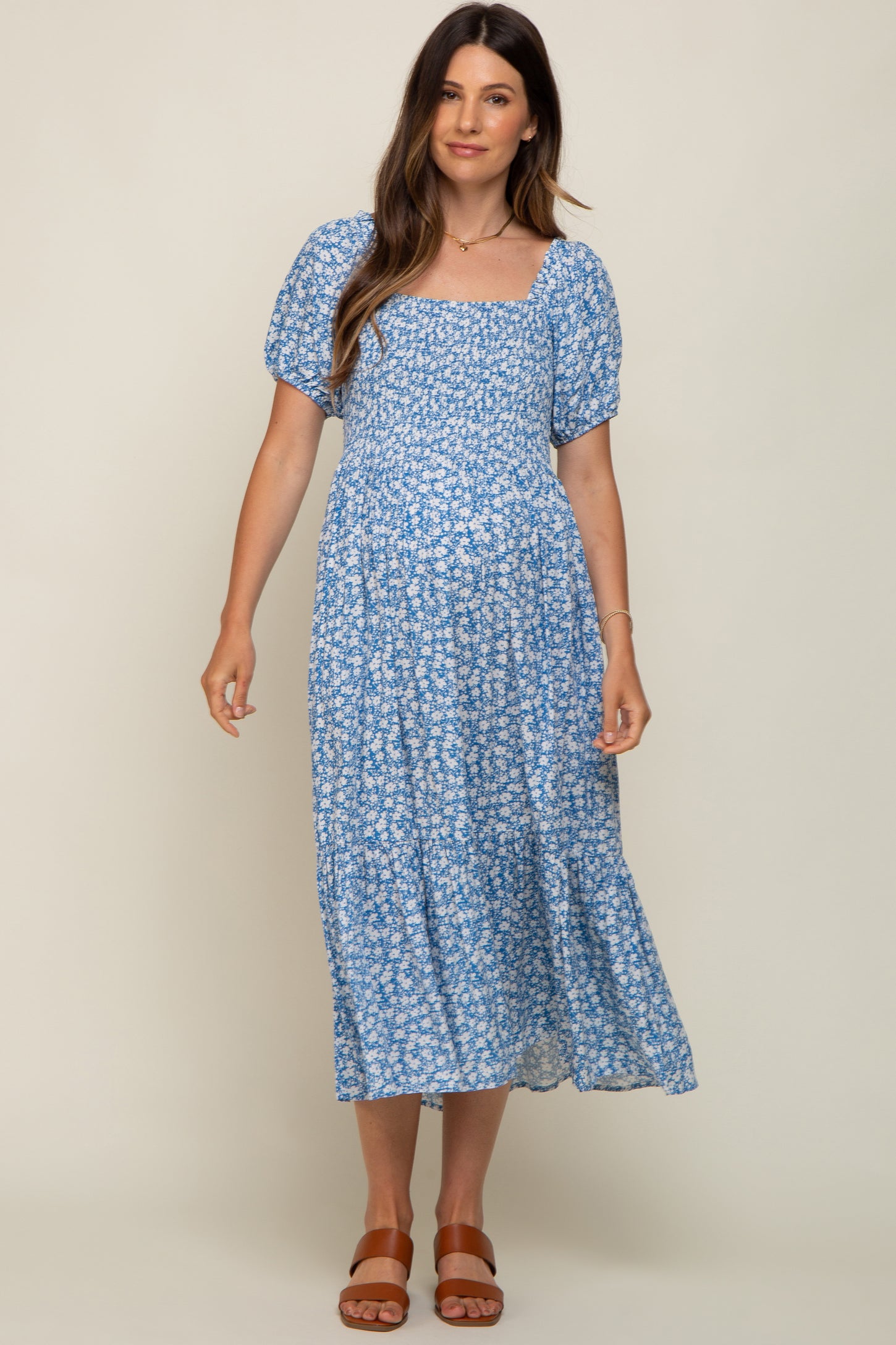 woman wearing a blue floral maternity dress with puff sleeves and a square neckline, showing her baby bump