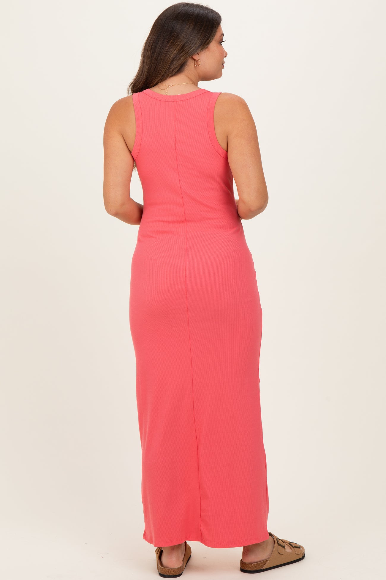 woman wearing a pink maternity maxi dress, shown from the back, highlighting a fitted style with a sleeveless design