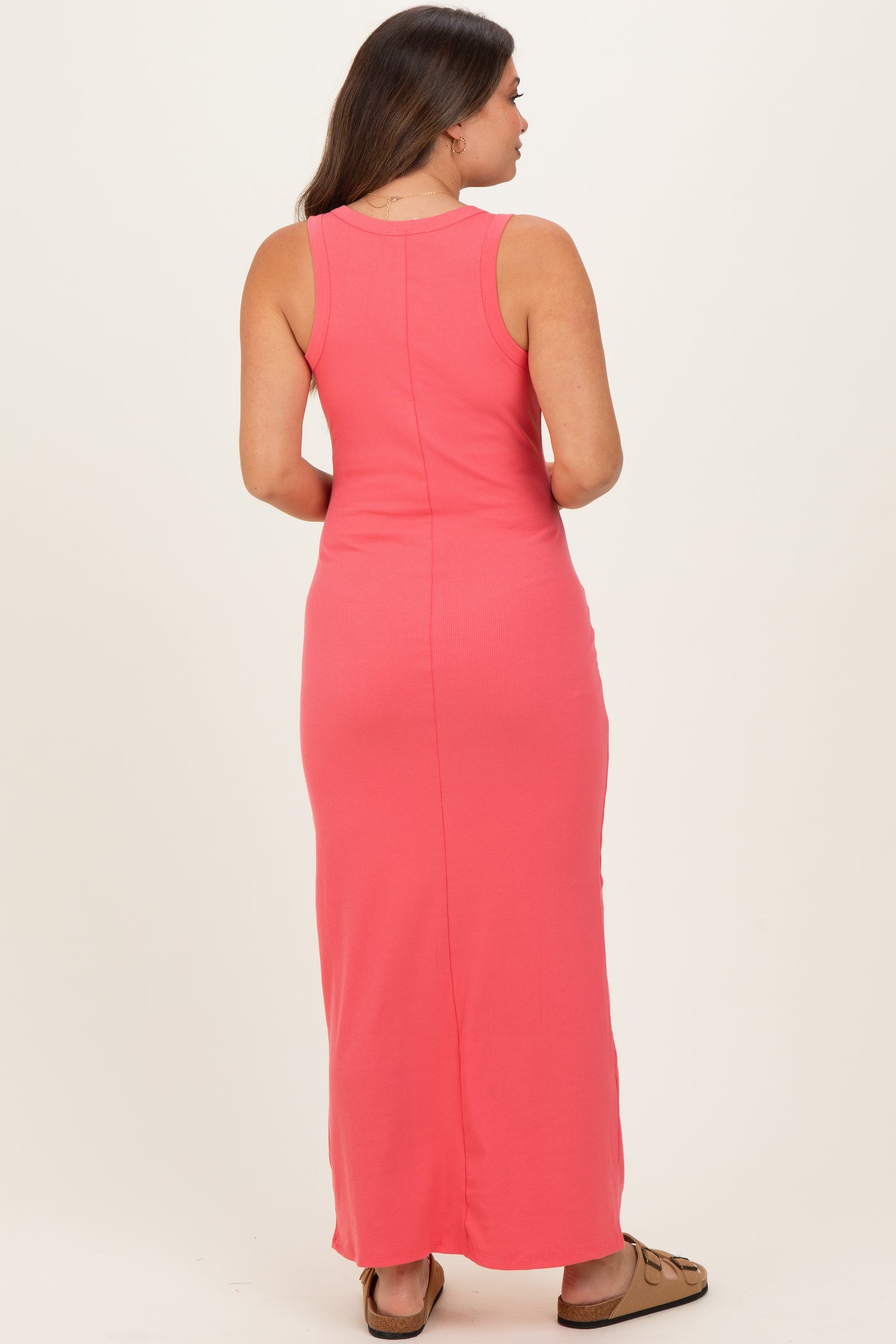 woman wearing a pink maternity maxi dress, shown from the back, highlighting a fitted style with a sleeveless design