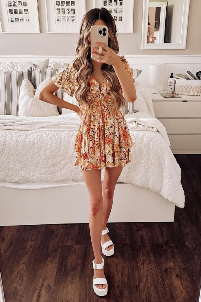 woman wearing a floral short sleeve dress with a layered skirt and white platform sandals, standing in a bright room