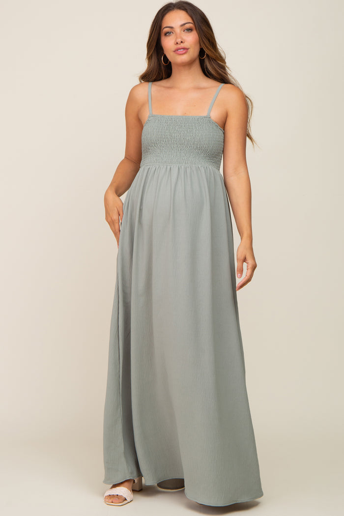 woman wearing a sage green smocked maternity maxi dress with spaghetti straps