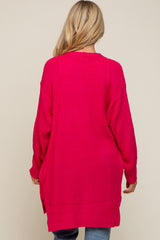 back view of a woman with blonde hair wearing a long hot pink oversized knit cardigan sweater