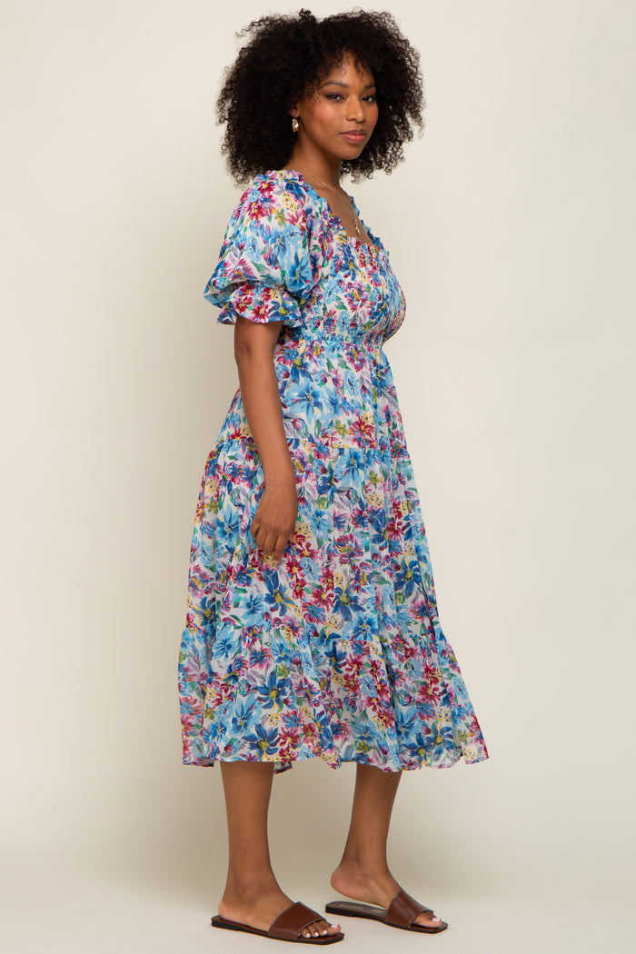 woman wearing a floral print midi dress with puff sleeves and a smocked bodice, standing against a neutral background
