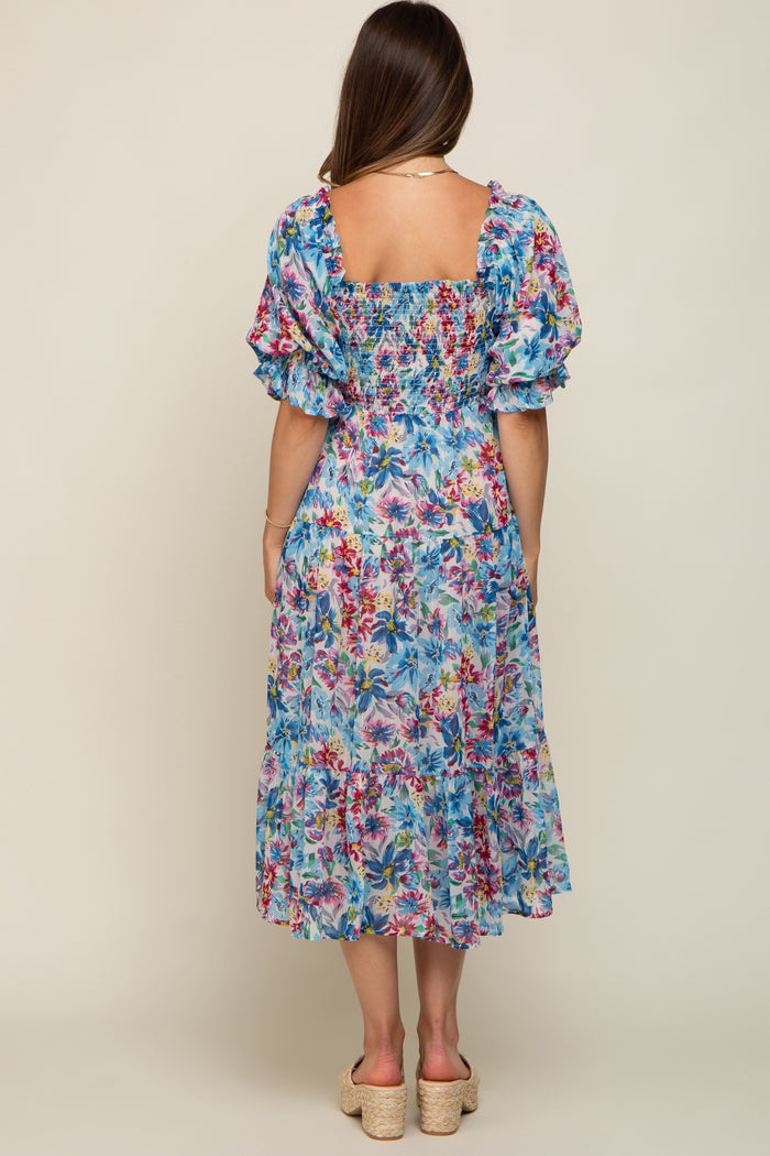 woman wearing a colorful floral maternity dress with puff sleeves and a smocked back, showing a relaxed fit