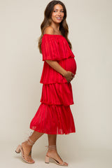 woman wearing a red off-the-shoulder tiered maternity dress and holding her baby bump