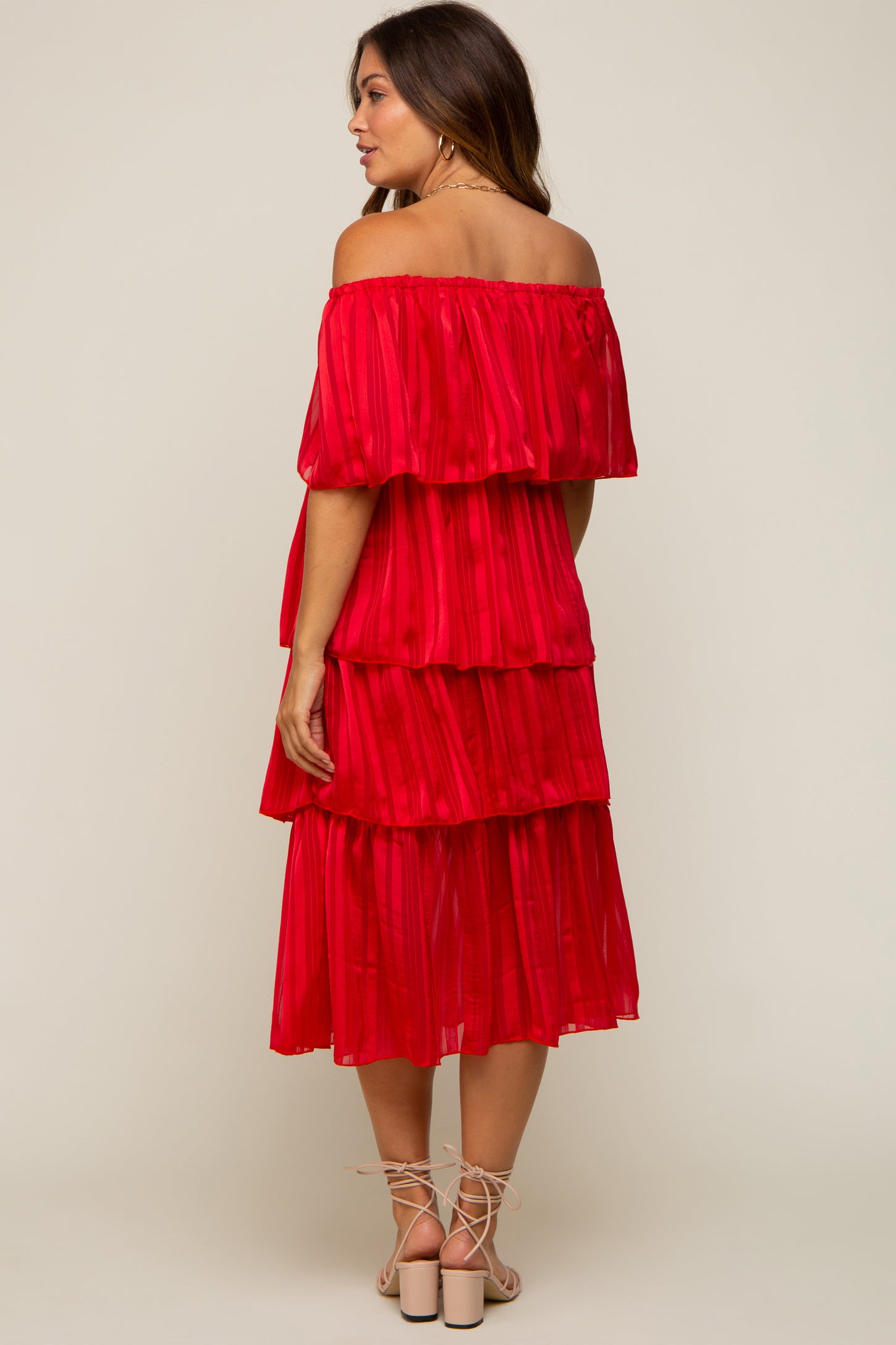 woman wearing a red off-the-shoulder tiered maternity dress with ruffle details and a flowing silhouette