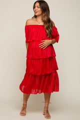 woman wearing a red tiered off-the-shoulder maternity dress and holding her baby bump