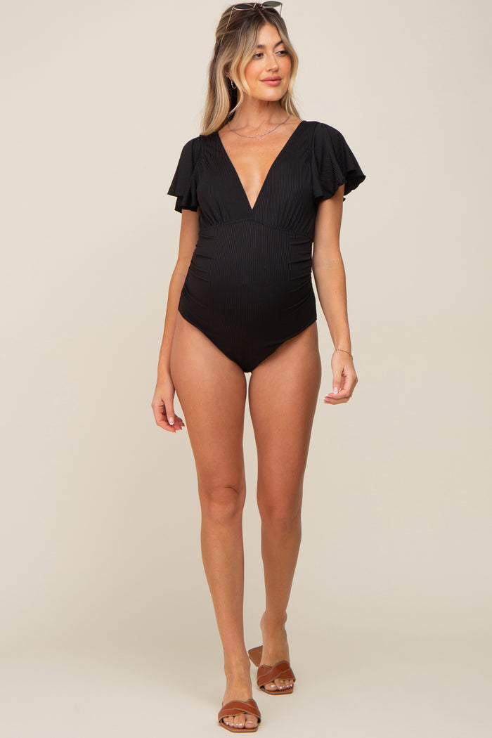 woman wearing a black striped maternity swimsuit with flutter sleeves and a deep v-neck, showing her baby bump