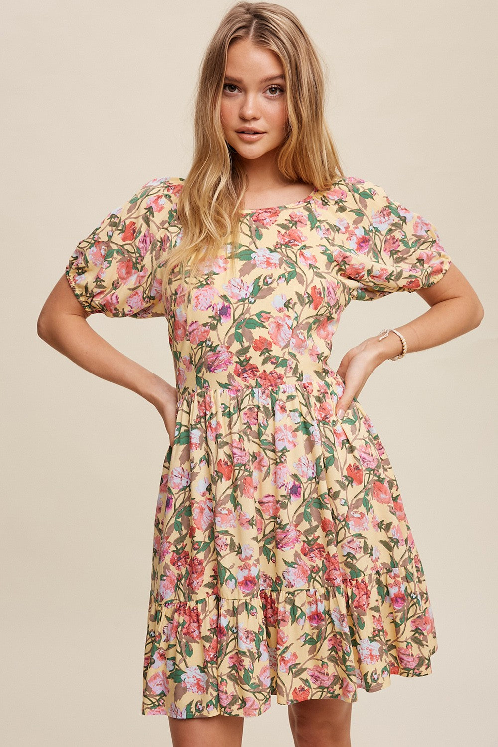 woman wearing a yellow floral puff sleeve mini dress with pink and red rose print