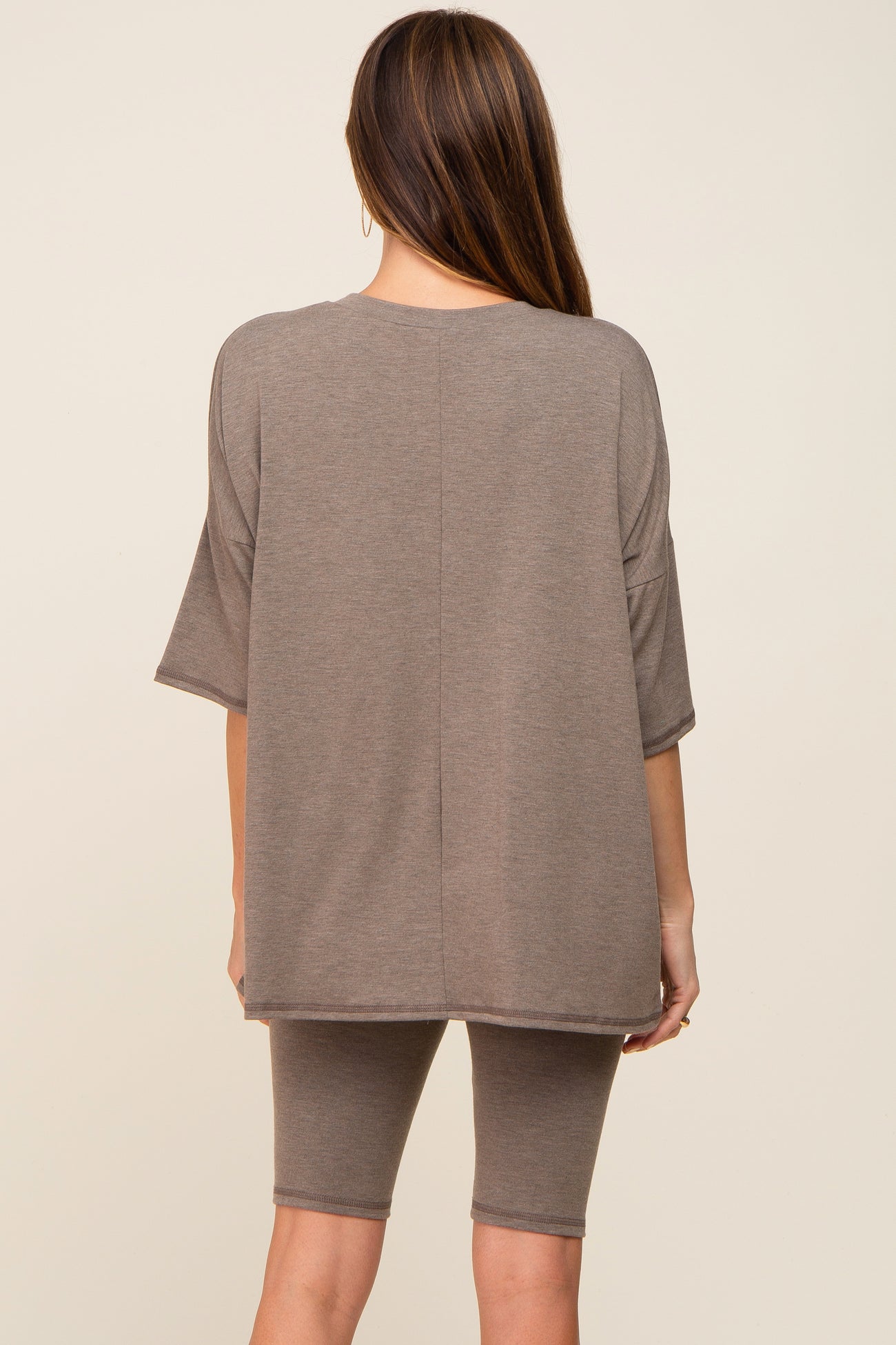 woman wearing a taupe oversized t-shirt and matching bike shorts, viewed from the back