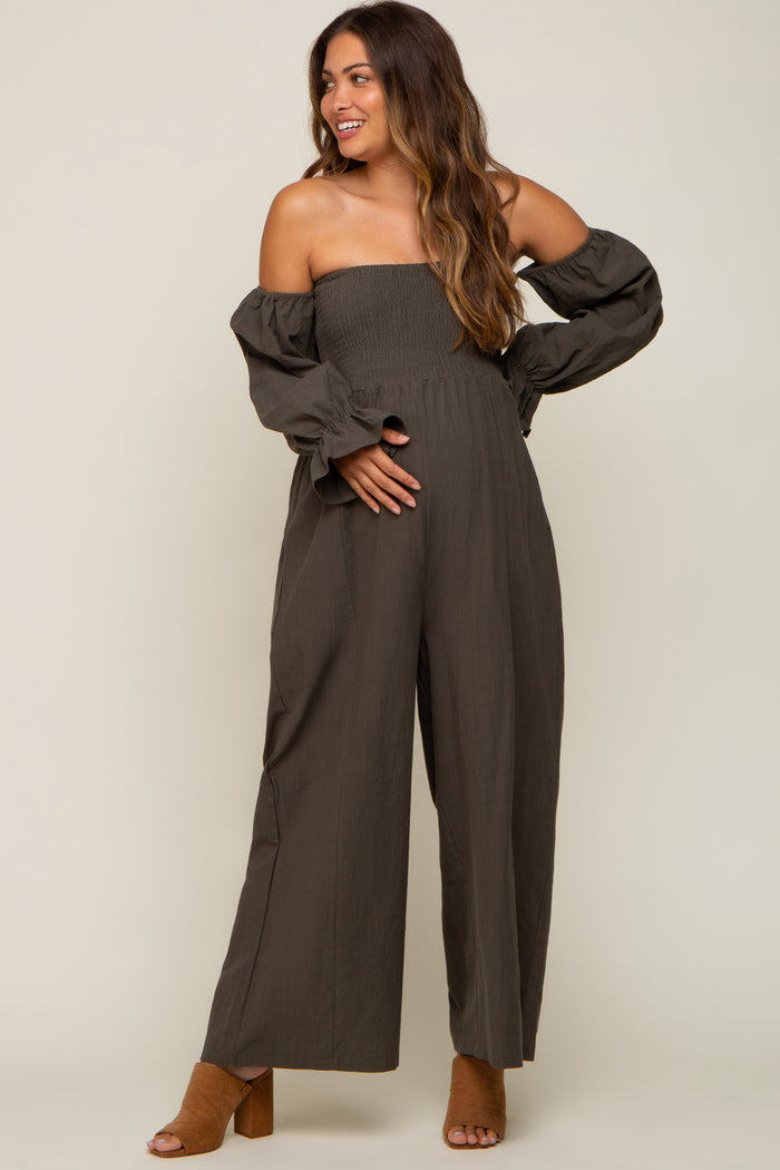 pregnant woman wearing an olive green off-the-shoulder smocked maternity jumpsuit with long sleeves