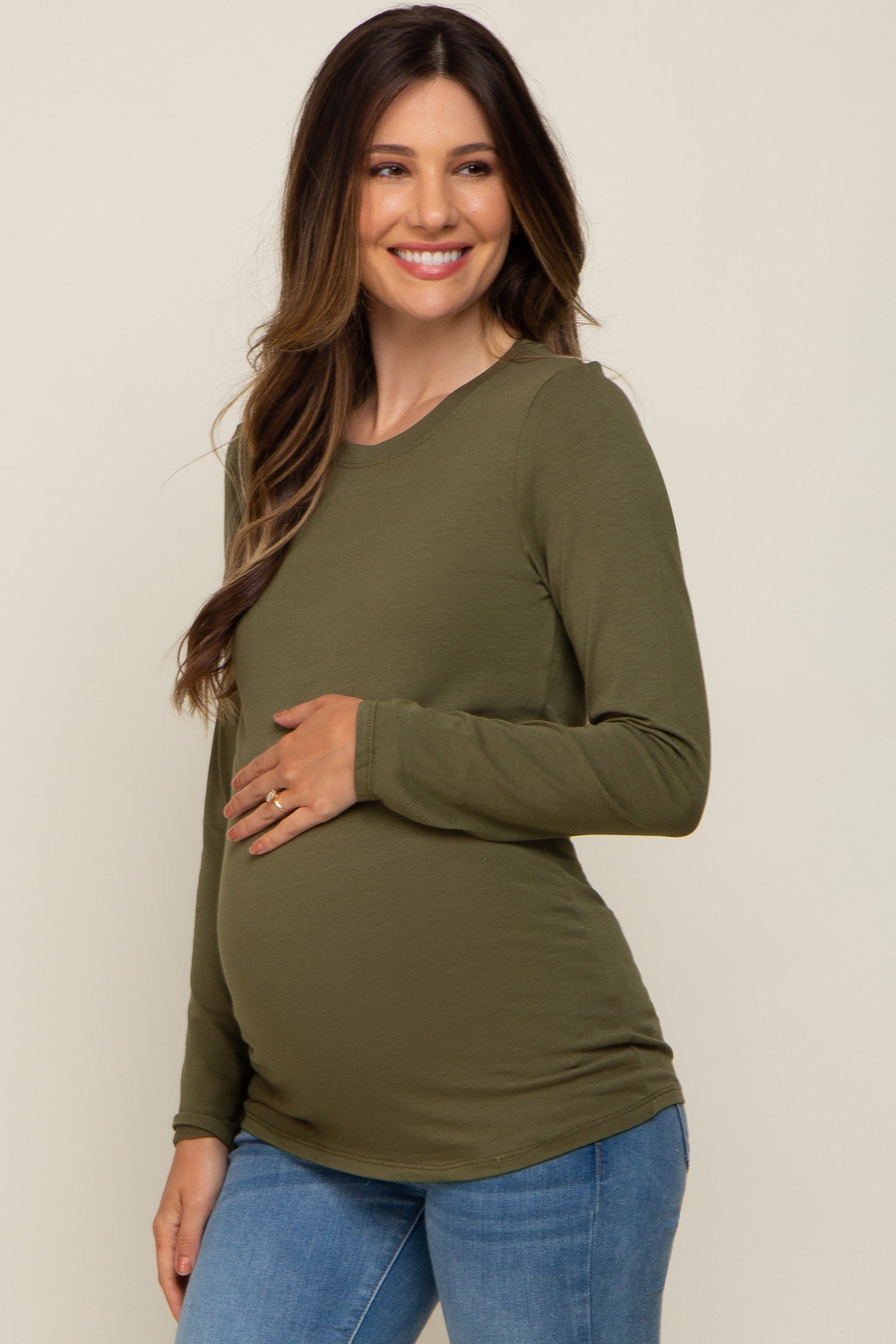 woman wearing a dark green long sleeve maternity top and showing her baby bump