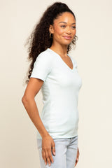 woman wearing a light blue short sleeve v-neck top with a fitted silhouette and curly hair styled down