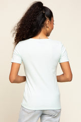 woman wearing a pastel green short sleeve top, seen from the back with curly hair styled up