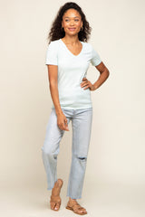 woman wearing a light mint green short sleeve v-neck t-shirt and light wash distressed jeans, standing and smiling