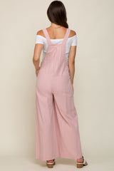 woman wearing a light pink maternity jumpsuit with wide legs and adjustable straps, showing her back