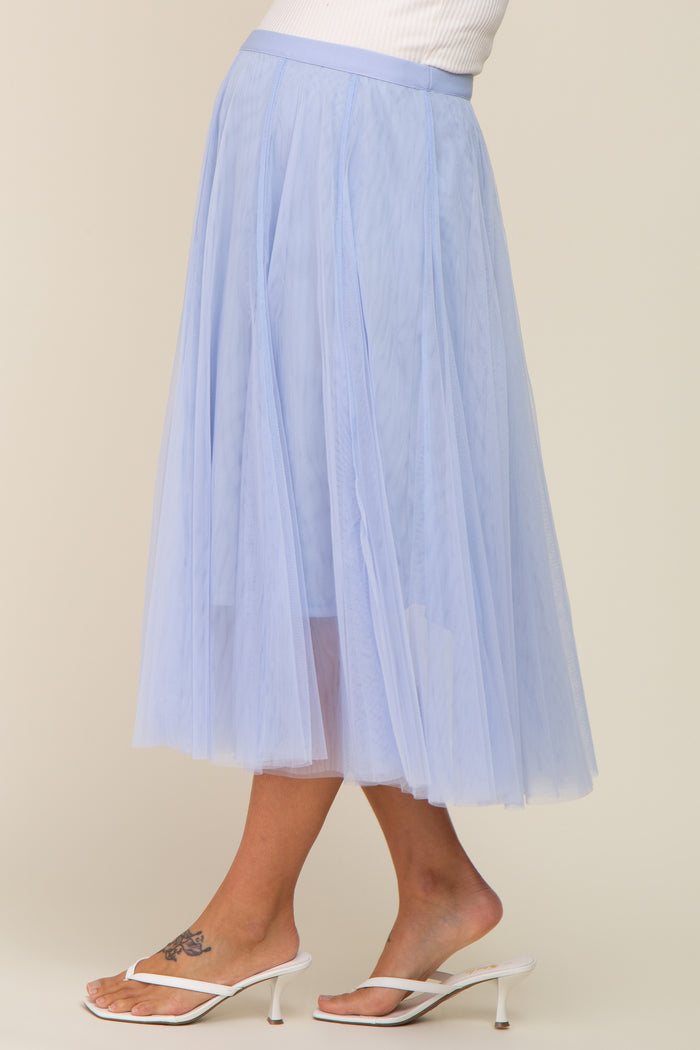 woman wearing a light blue tulle maternity skirt with a flowy design, standing in a side profile view