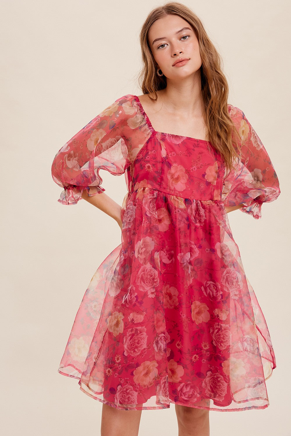 woman wearing a pink floral sheer dress with puff sleeves and a square neckline