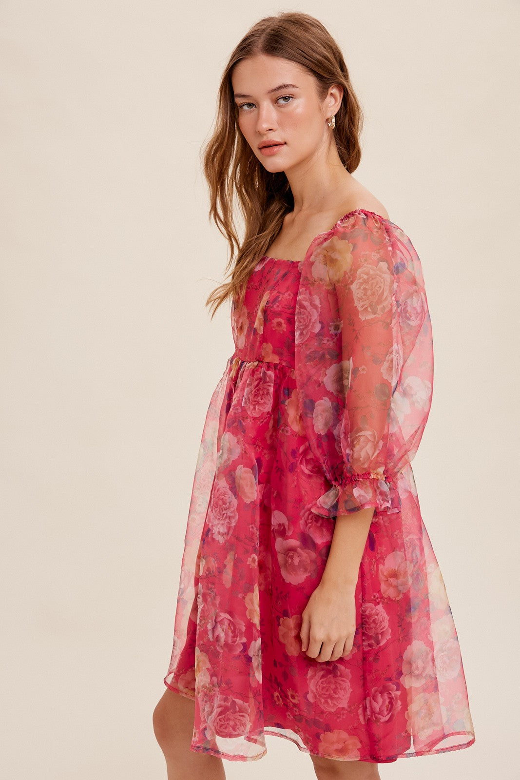 woman wearing a floral print pink mini dress with puff sleeves and a square neckline