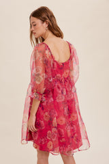 Woman wearing a pink floral puff sleeve mini dress with a square back and sheer organza fabric