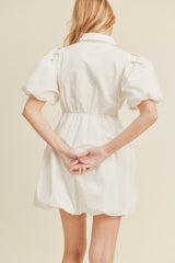 woman wearing a white puff sleeve mini dress with a cinched waist and a button-down collar, seen from the back