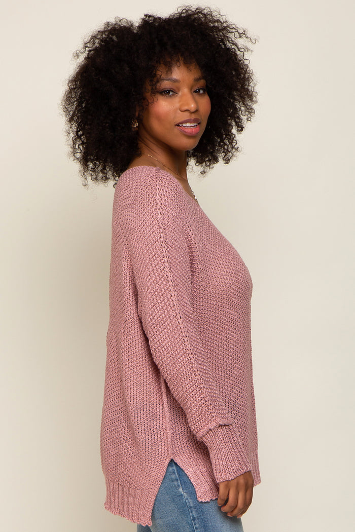 woman wearing a loose-fitting dusty pink knit sweater with side slits and long sleeves