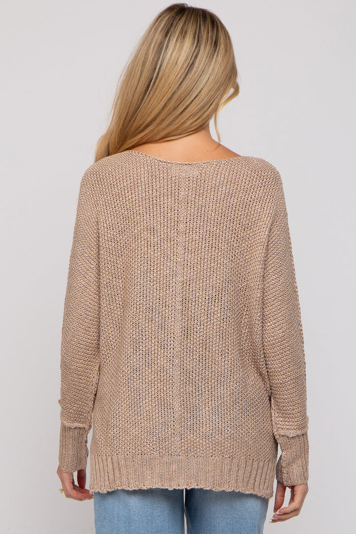 woman wearing a beige loosely knit maternity sweater with long sleeves, viewed from the back