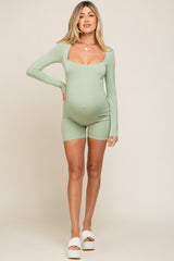 woman wearing a light green long sleeve maternity romper showcasing her baby bump