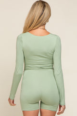 woman wearing a light green long sleeve maternity bodysuit from the back