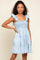woman wearing a light blue denim smocked mini dress with ruffle straps and tiered skirt