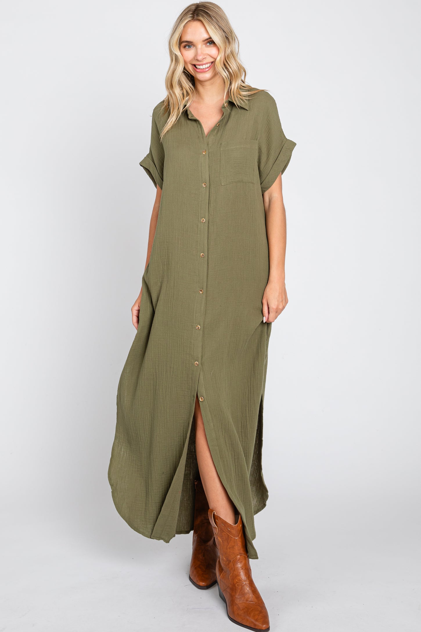 woman wearing an olive green button-up maxi dress with short sleeves and side slits, paired with brown cowboy boots