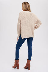 woman wearing a beige oversized knit sweater and blue skinny jeans with brown ankle boots