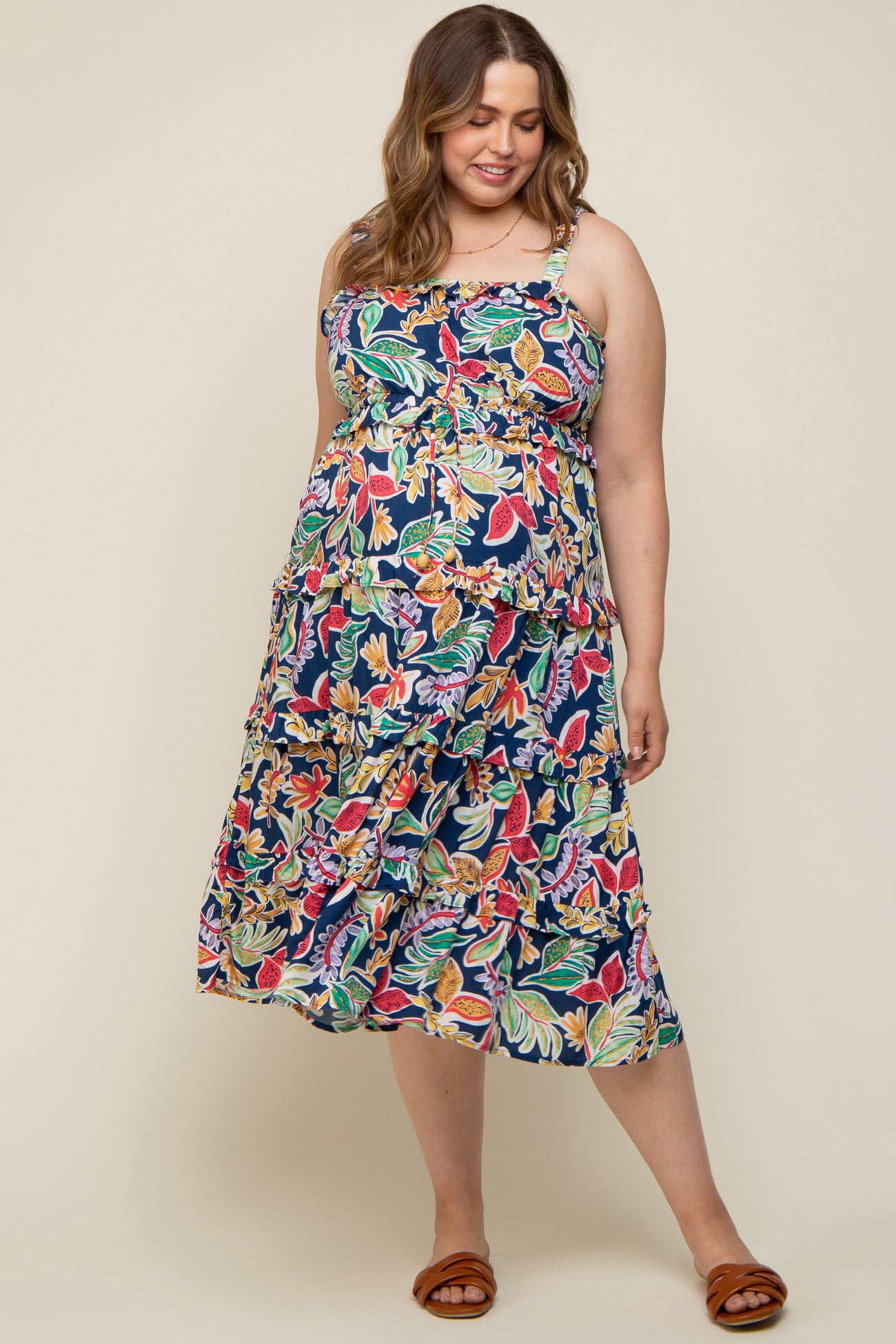 woman wearing a navy blue maternity plus dress with colorful floral print and a fitted bodice, showing her baby bump