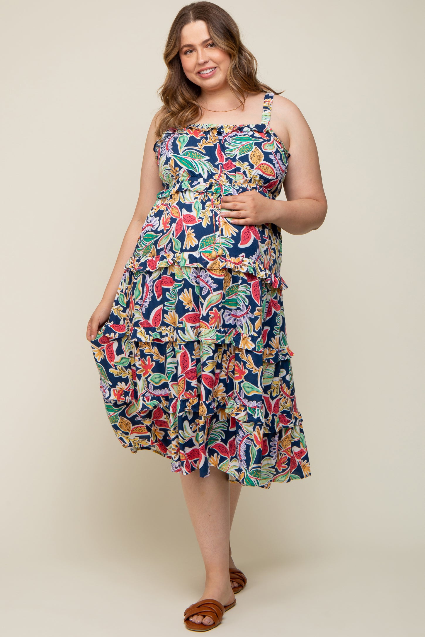 woman wearing a floral print maternity dress with ruffles in navy background, showing her baby bump