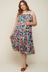 woman wearing a floral print maternity dress with ruffles in navy background, showing her baby bump
